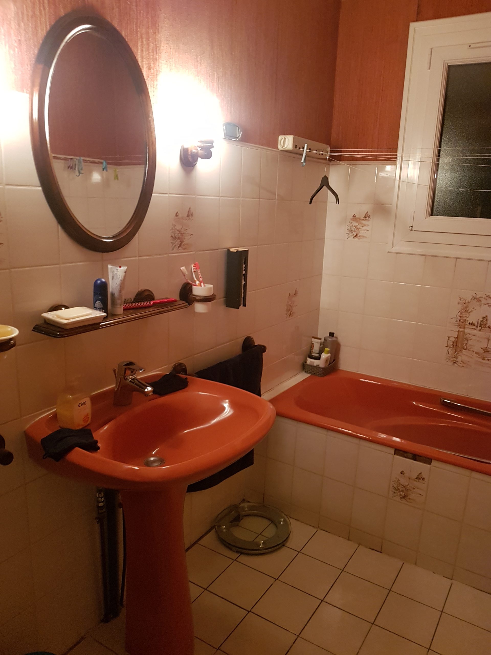 Photo d'une salle de bain avant rénovation, lavabo, baignoire et papier peint rouge