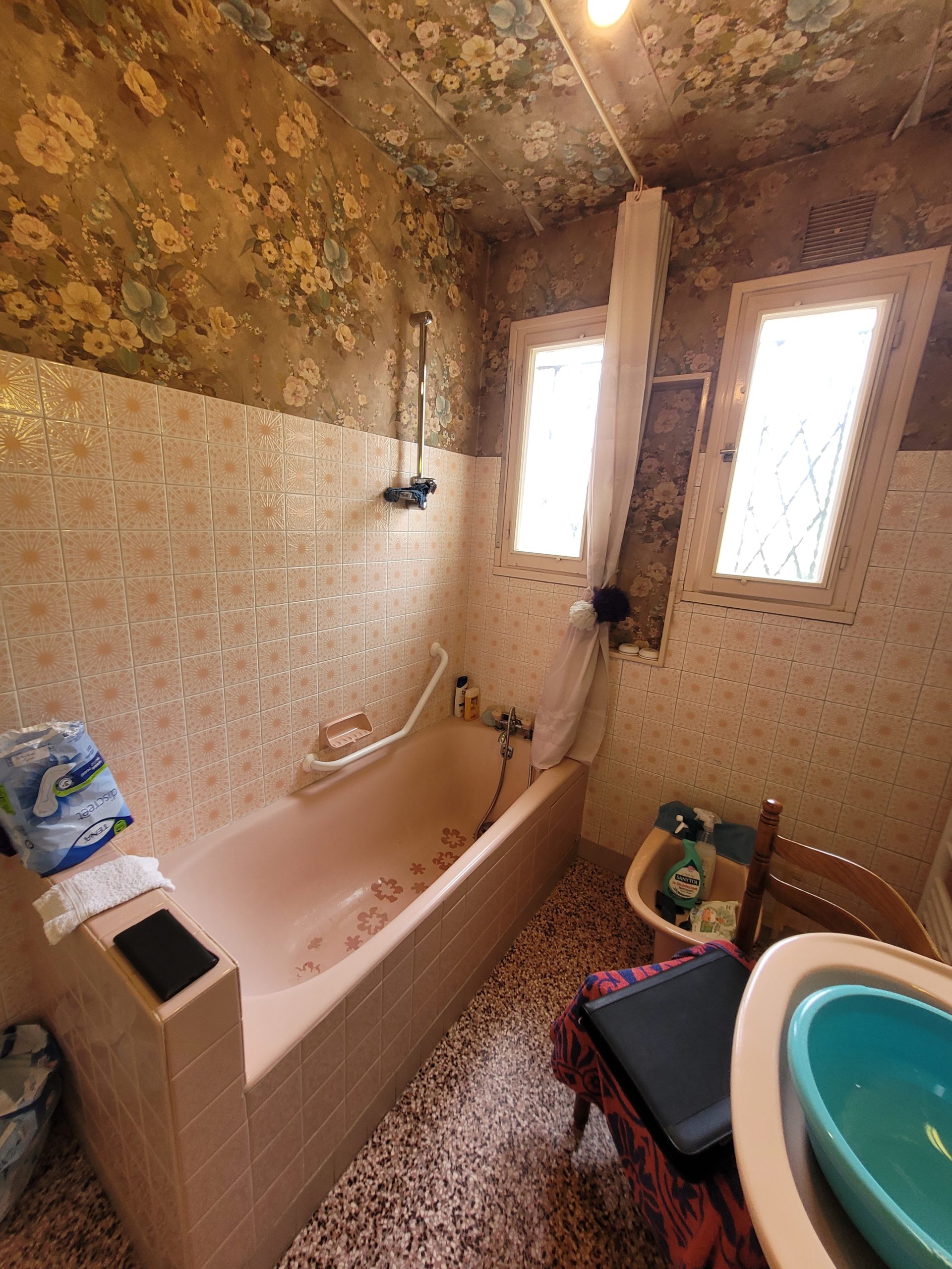 Photo d'une salle de bain avant rénovation avec baignoire et faïence rosé, sol en lino tacheté