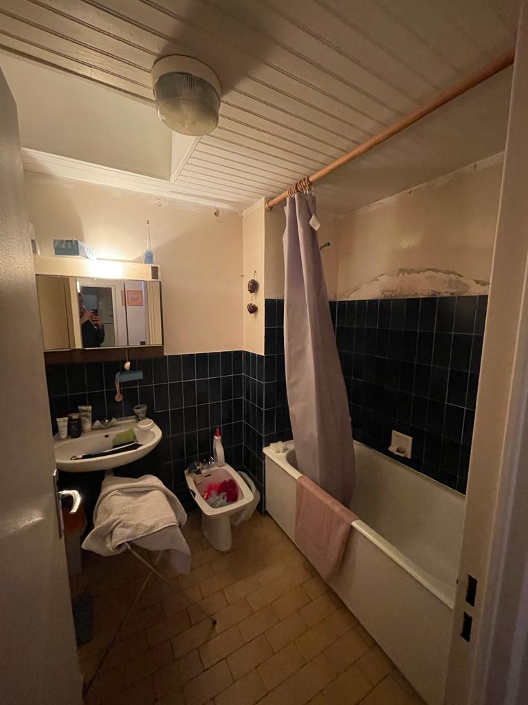 Photo d'une salle de bain avant rénovation avec faïence bleue, baignoire et mur détérioré