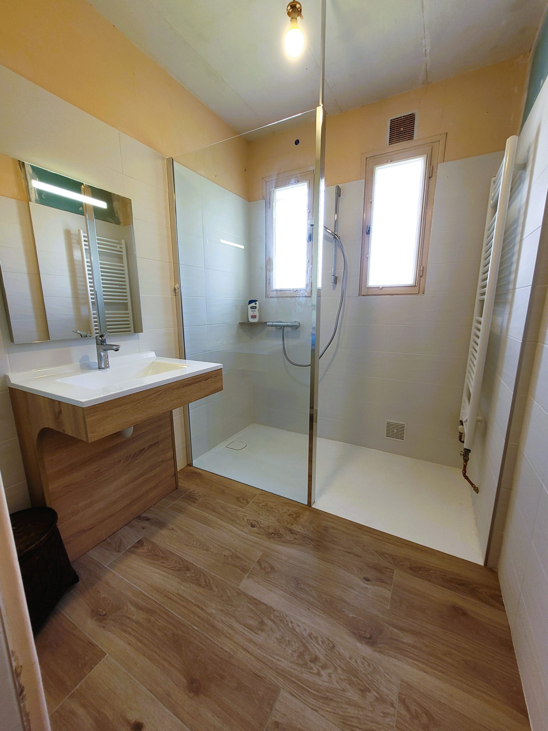 Photo d'une rénovation de salle de bain avec une grande douche à l'italienne, meuble vasque et un parquet.